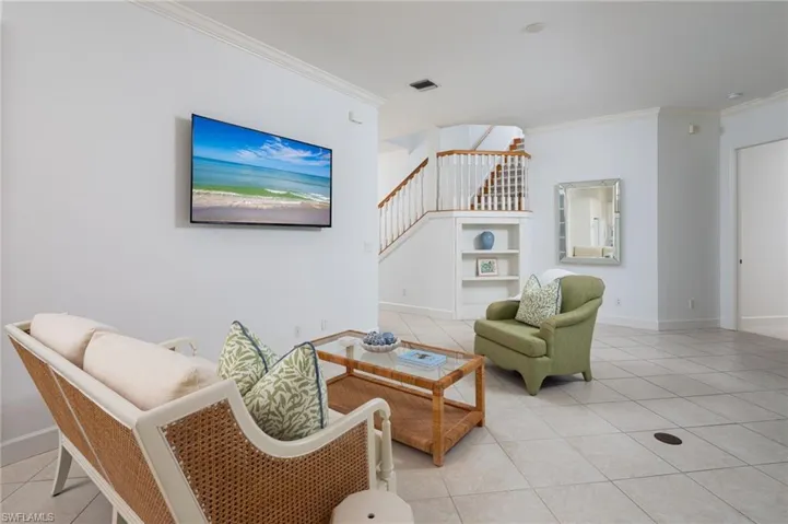 Living room featuring light tile patterned floors, stairway, and crown molding