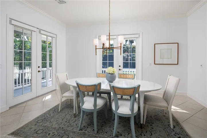 Dining room with french doors, light tile patterned floors, crown molding, and a chandelier