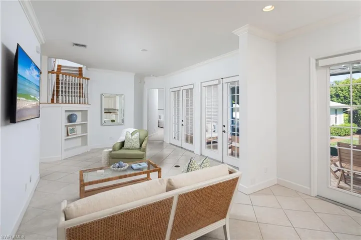 Living room featuring light tile patterned flooring, french doors, crown molding, plenty of natural light, and built in shelves