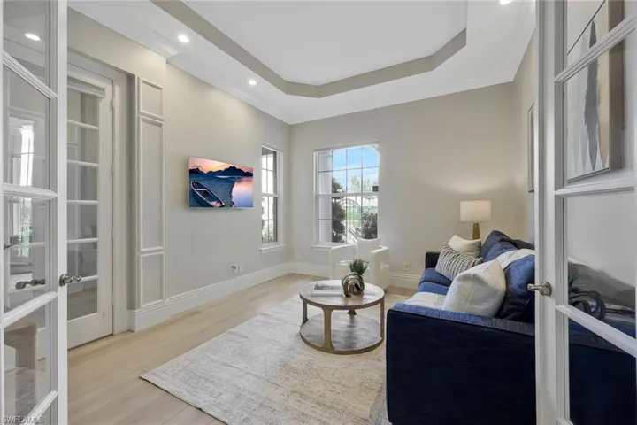 Living area with light wood-type flooring, french doors, a raised ceiling, recessed lighting, and ornamental molding