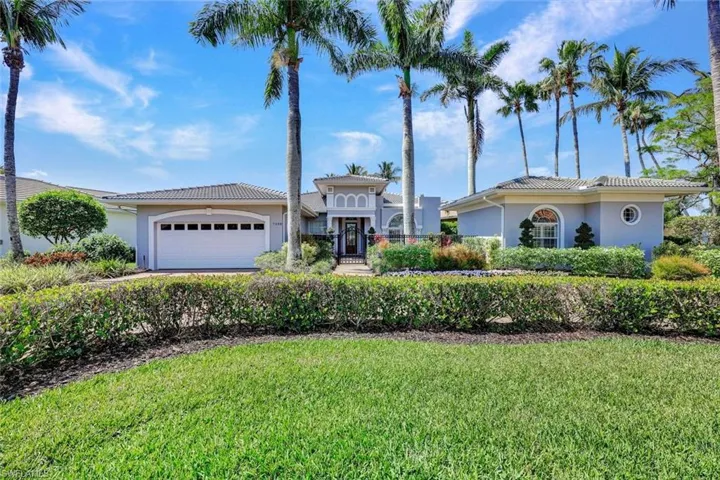 Mediterranean / spanish house with stucco siding, a front yard, an attached garage, and a tiled roof