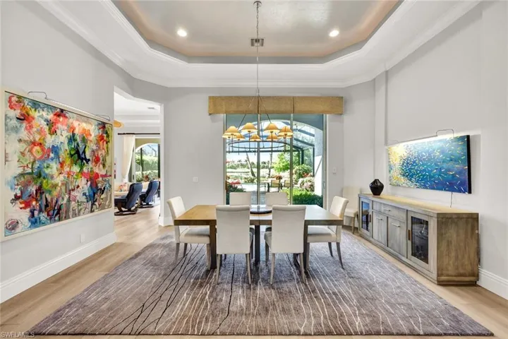 Dining room featuring a raised ceiling, light wood-style flooring, a chandelier, ornamental molding, and recessed lighting