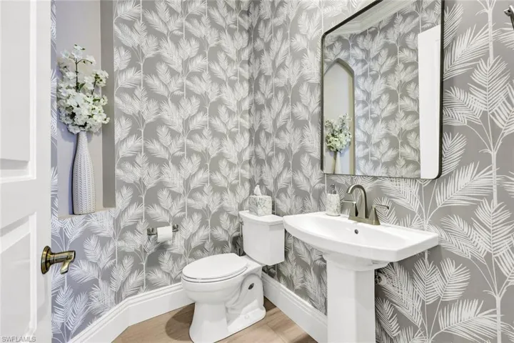 Hall bathroom with wallpapered walls and baseboards