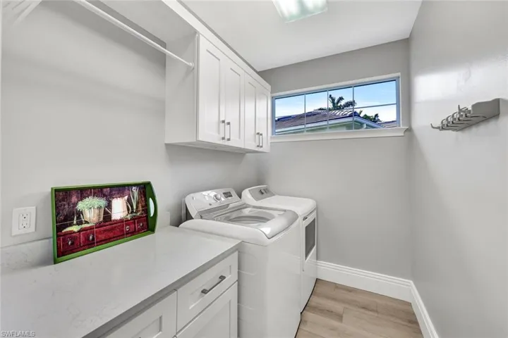 Laundry area with light wood-style flooring, cabinet space, and separate washer and dryer