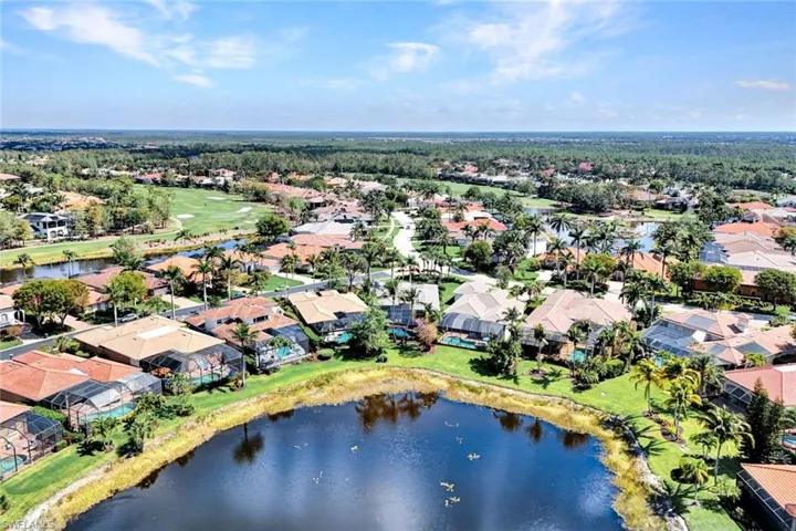 Aerial view of residential area featuring a nearby body of water and a golf club