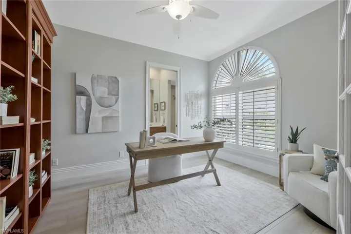 Home office/ bedroom with light wood finished floors, ceiling fan, and crown molding. Built in murphy bed, ensuite full bath and walk in closet.