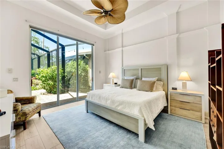 Bedroom with light wood finished floors, a ceiling fan, access to exterior, and a raised ceiling