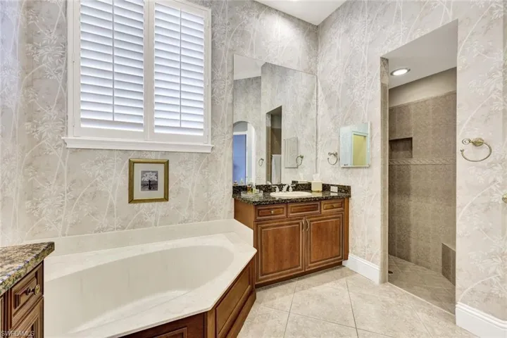 Bathroom with a bath, vanity, light tile patterned flooring, walk in shower, and wallpapered walls