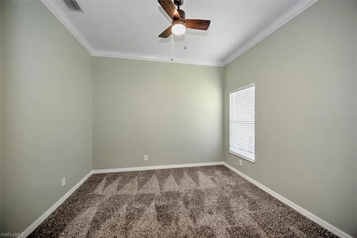 Carpeted spare room with ceiling fan and crown molding