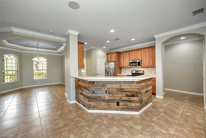 Kitchen featuring stainless steel appliances, an inviting chandelier, crown molding, and light tile floors