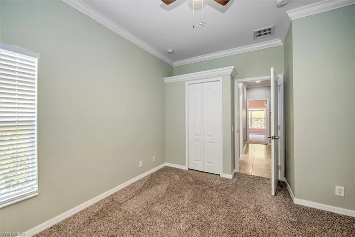 Unfurnished bedroom featuring crown molding, carpet flooring, a closet, and ceiling fan