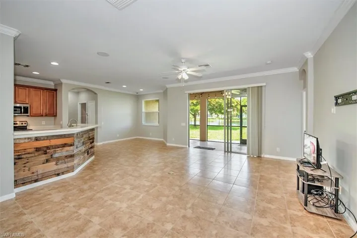 Living room featuring ceiling fan, crown molding, sink, and light tile floors