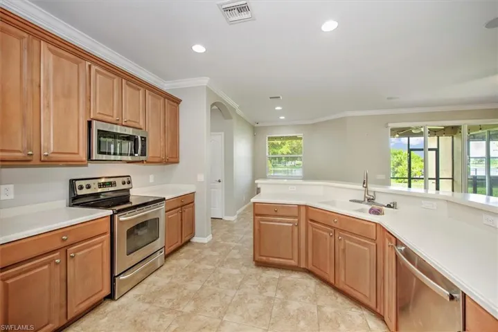 Kitchen with sink, light tile floors, ornamental molding, and appliances with stainless steel finishes