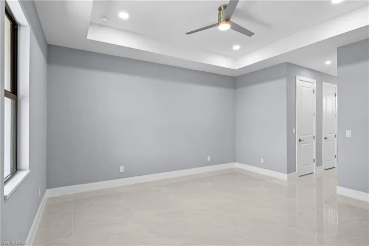 Spare room with a raised ceiling, ceiling fan, and light tile floors
