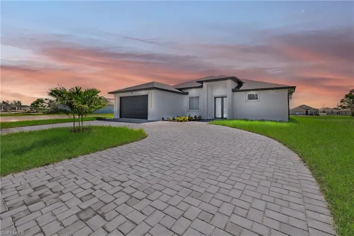 Single story home featuring a garage and a lawn