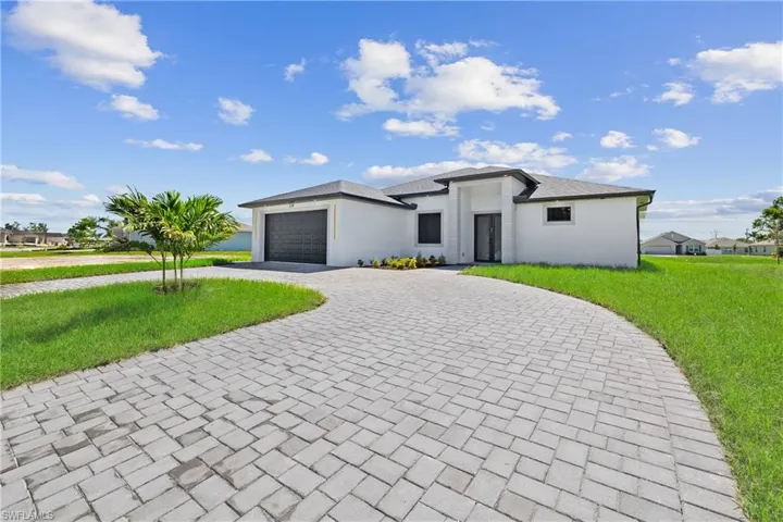 View of front facade featuring a garage and a front lawn