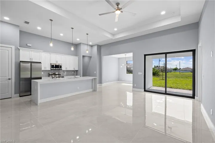 Kitchen with a center island with sink, stainless steel appliances, a tray ceiling, backsplash, and pendant lighting