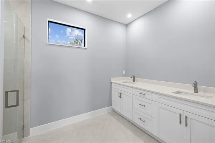 Bathroom featuring tile floors, a shower with shower door, and double sink vanity