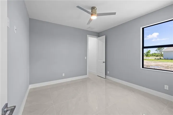 Unfurnished room featuring ceiling fan and light tile floors