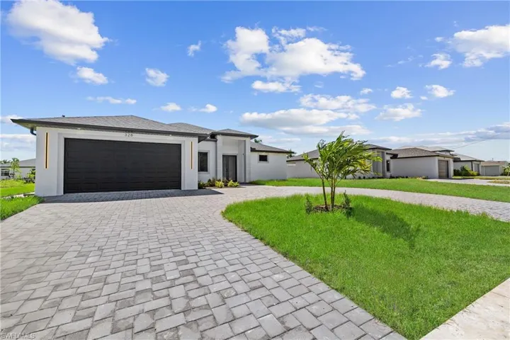 View of front of property with a garage and a front lawn