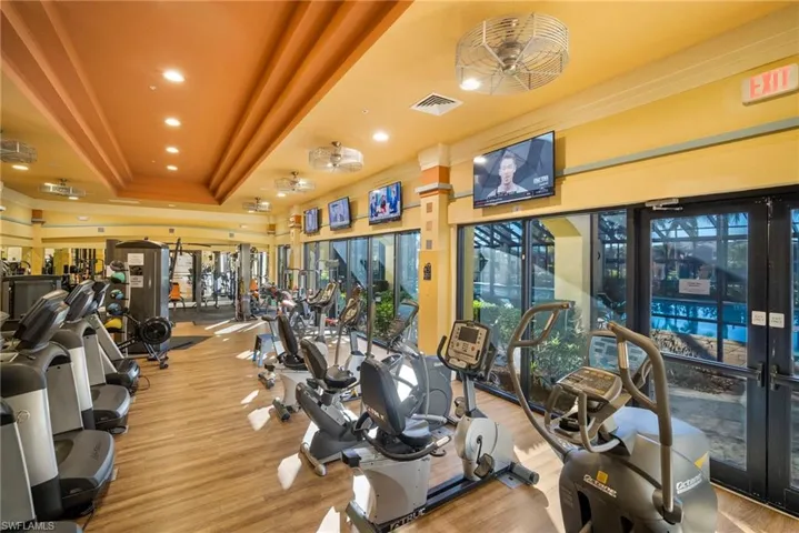 Workout area with a raised ceiling, ornamental molding, wood finished floors, and recessed lighting