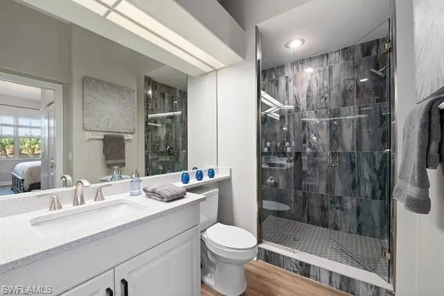 Full bathroom with vanity, a stall shower, ensuite bathroom, and wood finished floors