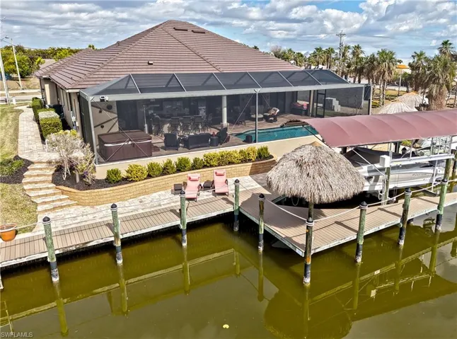 Dock featuring boat lift, Picture Screens all around lanai enclosure, a hot tub, heated saltwater pool. This photo is virtually staged