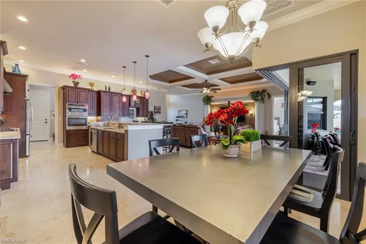Dining room with ornamental molding, coffered ceiling, a chandelier, beam ceiling, and ceiling fan