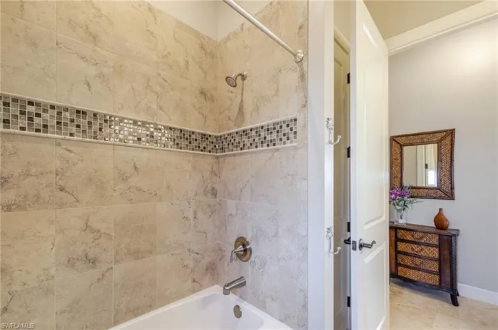 Bathroom with shower / washtub combination and baseboards