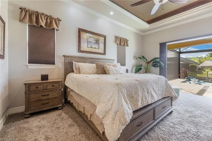 Bedroom featuring a raised ceiling, light colored carpet, ornamental molding, access to exterior, and a sunroom