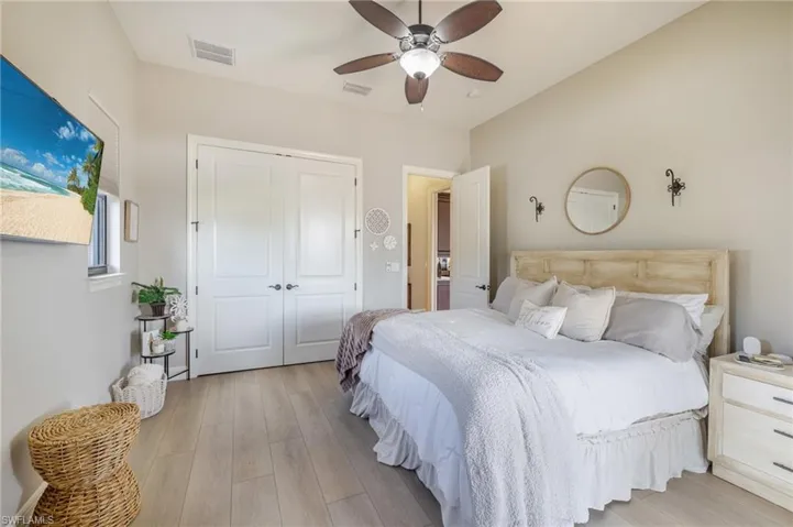 Bedroom with light wood finished floors, ceiling fan, and a closet