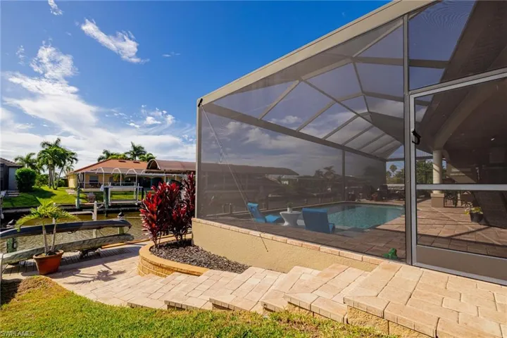 Swimming pool featuring glass enclosure, a patio, and a sunroom
