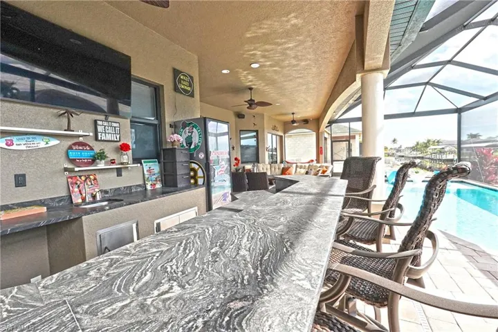 View of Custom-built outdoor kitchen with leather granite countertop, grill, wet bar, inground heated saltwater pool