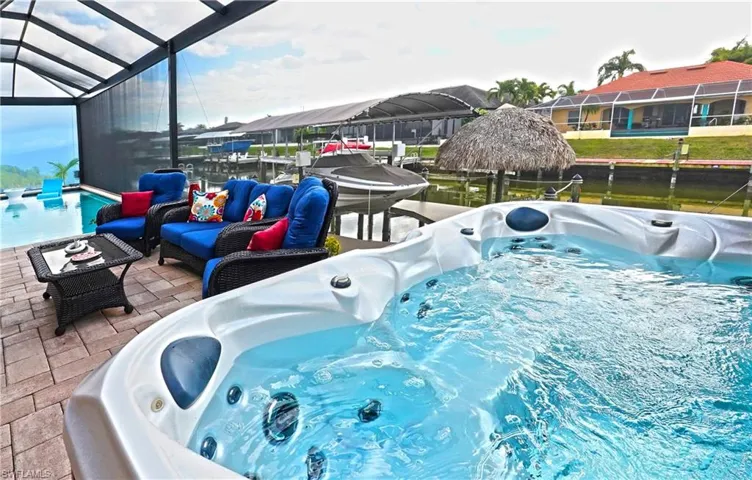 Outdoor pool featuring a hot tub, a sunroom, an outdoor living space, a patio, and a dock