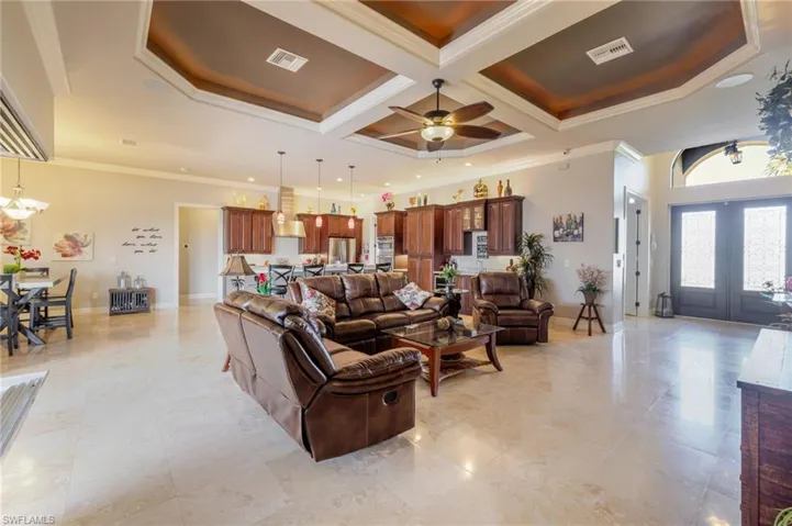 Living area with crown molding, coffered ceiling, a chandelier, beam ceiling, and french doors