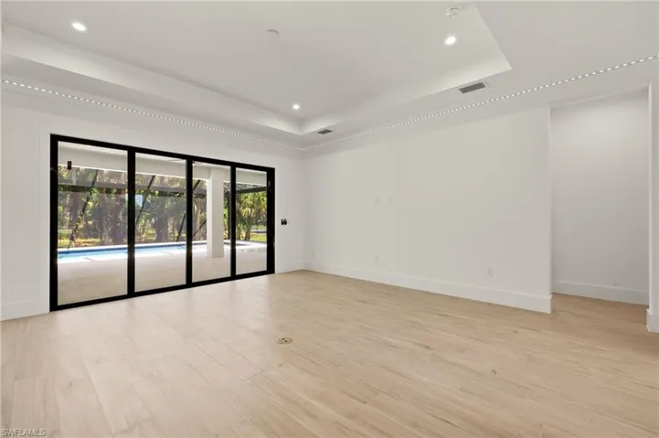 Unfurnished room with light wood-style floors, visible vents, baseboards, and a raised ceiling