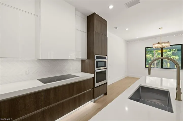 Kitchen featuring light countertops, white cabinetry, visible vents, modern cabinets, and a sink