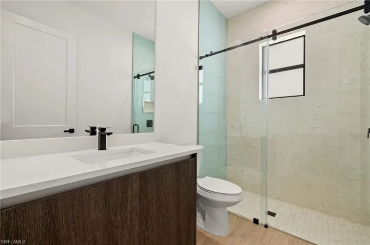 Full bathroom featuring a shower stall, vanity, toilet, and wood finished floors