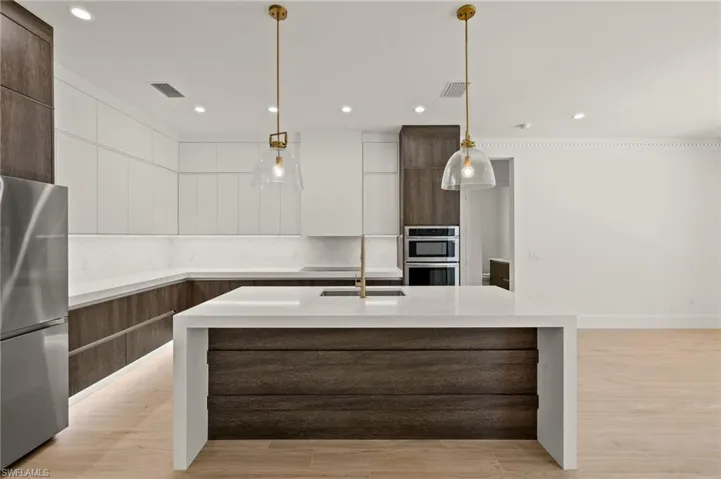 Kitchen with stainless steel appliances, light countertops, modern cabinets, and backsplash