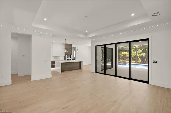 Unfurnished living room with recessed lighting, light wood-type flooring, visible vents, and a tray ceiling
