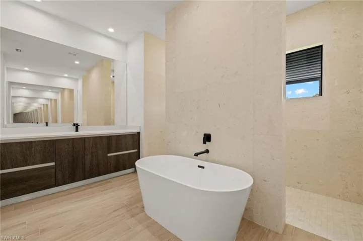 Full bath featuring tile walls, vanity, wood finished floors, walk in shower, and a freestanding bath