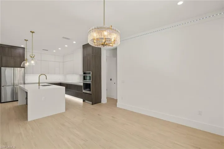 Kitchen featuring a chandelier, an island with sink, modern cabinets, stainless steel appliances, and a sink