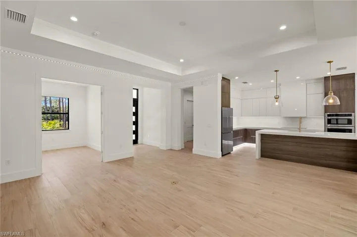 Unfurnished living room with a raised ceiling, baseboards, visible vents, and light wood-style flooring
