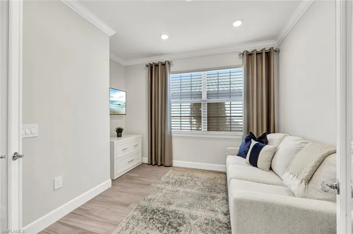 Sitting room with light wood-type flooring, ornamental molding, and recessed lighting