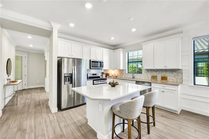 Kitchen featuring appliances with stainless steel finishes, white cabinetry, a kitchen bar, light wood-type flooring, and a kitchen island