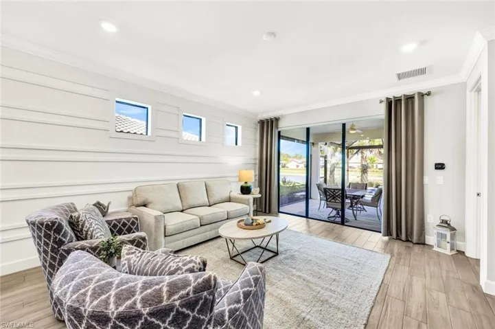 Living area featuring light wood-style flooring, healthy amount of natural light, ornamental molding, and recessed lighting