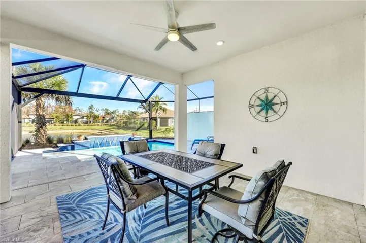 View of patio / terrace featuring a sunroom, a ceiling fan, an outdoor pool, outdoor dining area, and glass enclosure