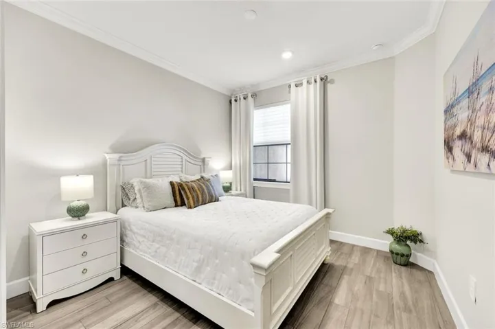 Bedroom with light wood finished floors and crown molding