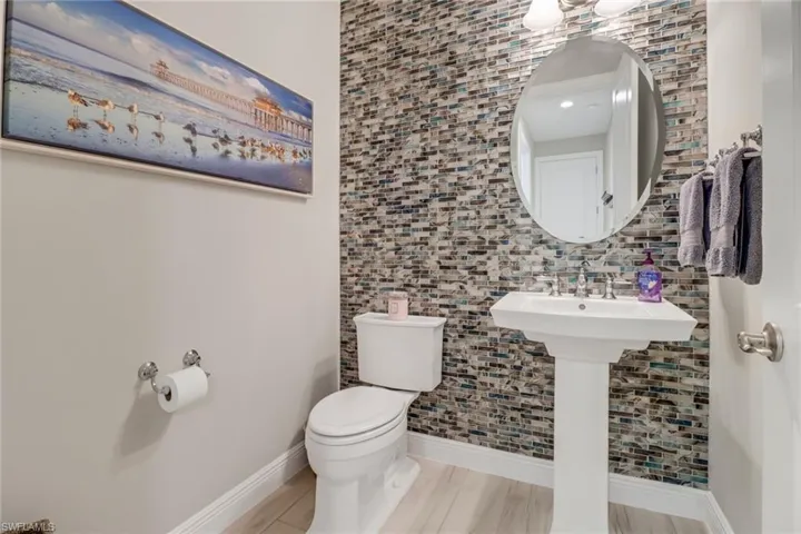 First floor powder room with tile walls, tasteful backsplash