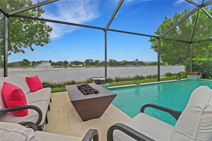 View of pool with a fire pit, a patio, and glass enclosure